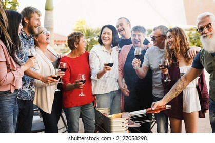 Multi Generational Friends Having Fun At Barbecue Dinner Outdoor - Focus On Man Hand Cooking Meat