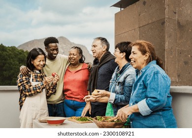 Multi generational friends having fun cooking together at house rooftop - Summer gatherings and food concept - Powered by Shutterstock