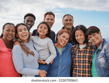 Multi generational friends smiling on camera outdoor - Group of multiracial people with different ages having fun together outdoor - Powered by Shutterstock