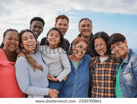Multi generational friends smiling on camera outdoor - Group of multiracial people with different ages having fun together outdoor