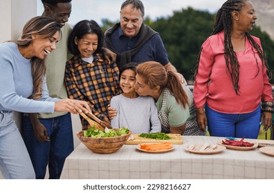 Multi generational people cooking at house terrace rooftop - Multiracial friends preparing food with  female child outdoor during weekend day - Grandmother having tender moment with granddaughter - Powered by Shutterstock