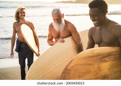 Multi generational surfer friends having fun on the beach after surf session - Focus on senior man face - Powered by Shutterstock