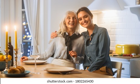 Multi Generations Of Beautiful Women In Kitchen. Elderly Mother And Mature Daugher Sit At A Table And Hug, Have Fun And Smile On Camera. Lovely Family Dinner With Generations Reunion.