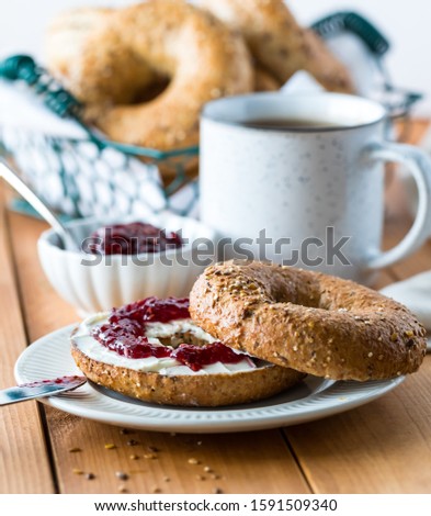A multi grain bagel with cream cheese and jam.