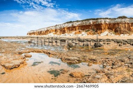 A multi image panorama of the dramatic colours looking over the rock pools towards the colourful cliffs at Hunstanton under a blue sky.