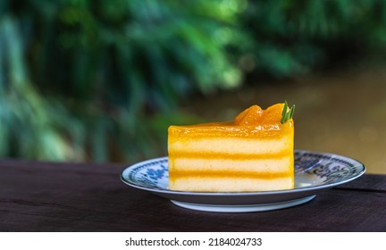 Multi layer orange cake topped with orange marmalade, sliced ​​orange and rosemary leaves.Placed in a plate and with a spoon placed on its side