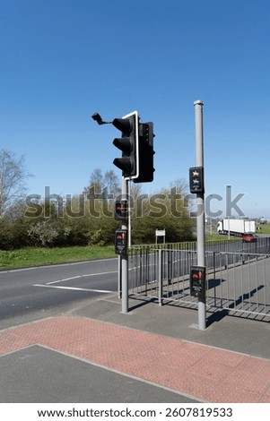 Multi level, high, low and standard push button traffic lights for pedestrians, cyclists and horse riders next to a road against a blue sky.
