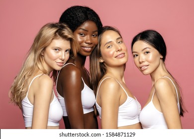 Multi Racial Ethnic Group Of Womans With Diffrent Types Of Skin Standing Together And Looking On Camera. Diverse Ethnicity Women - Caucasian, African And Asian Against Pink Background