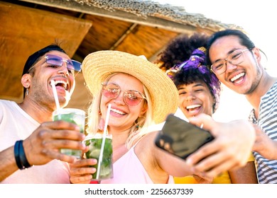 Multi racial friends taking a selfie at the beach - Group of young people toasting with mojito at kiosk in the summertime - Holidays, fun, happy lifestyle concept