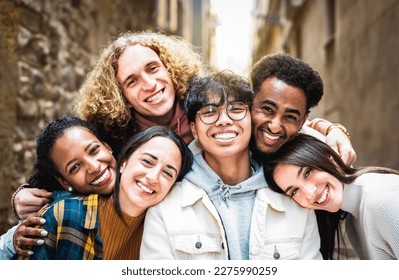 Multi racial guys and girls taking selfie outdoors with backlight - Happy life style friendship concept on young multiracial best friends having fun day together in Barcelona city - Warm vivid filter - Shutterstock ID 2275990259