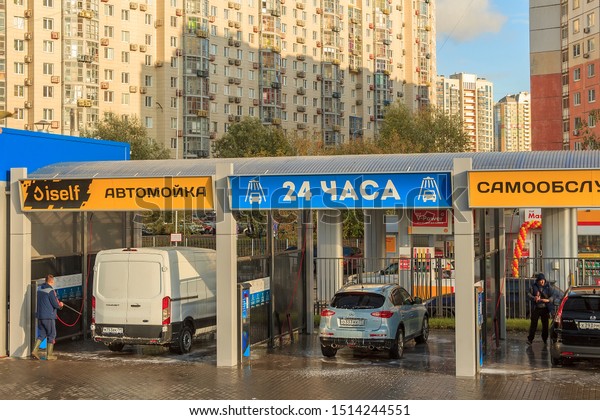 multi-bay, coin-operated self-service car wash in\
Krasnogorsk Moscow region Russia September 2019. Self clean car\
wash. 24 hours. Around clock. Busy man in jeans and blaser is\
washing his own car