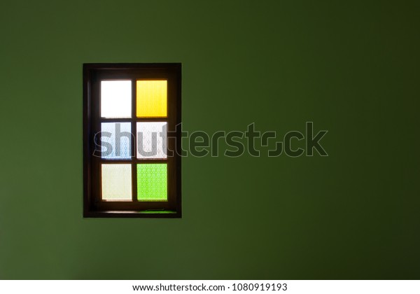 Multicolor glass\
window with green wall dark background. Single colorful glass\
window with dark green wall\
surface