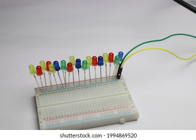 Multicolor LED are connect to solderless breadboard laid flat on white background which shows electrical hobby projects concept