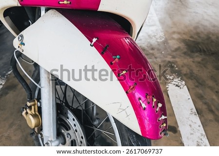 Multicolor nylon cable ties mounting on front broken motorcycle or scooter fender or mudguard. Motorcycle or motorbike fender or mudguard cracked and tied with cable ties to keep it from coming apart