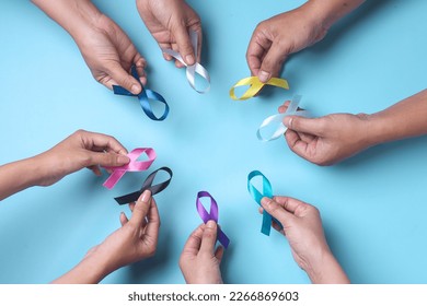 Multi-color ribbons on hands isolated on blue. Cancer awareness, World cancer day. - Powered by Shutterstock