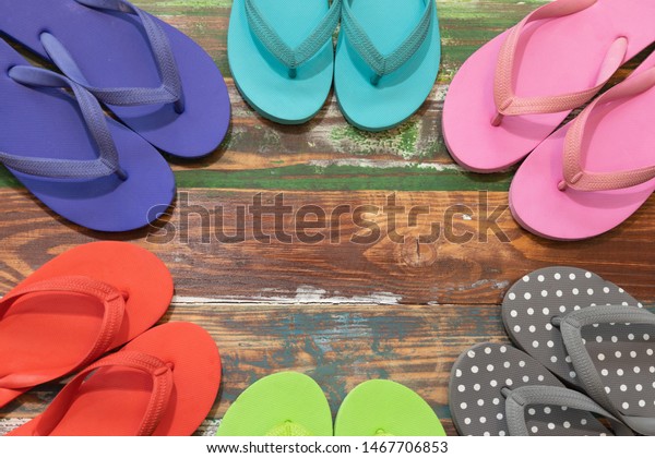 Multi-color slippers\
on a brown-green wood floor. Concept of the sea or the slum\
community Children are destitute Orphan foundation Children playing\
together. Wooden\
background