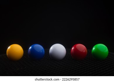 Multi-colored balls on a black background lined up in a colored line