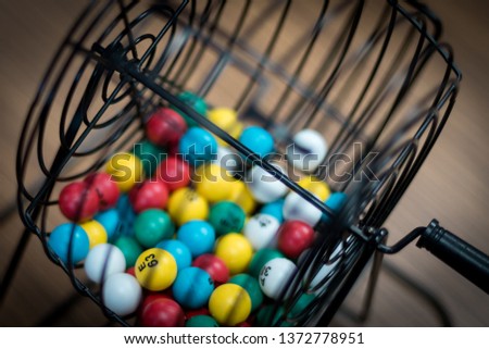 Multi-colored bingo balls in cage sitting on a desk.