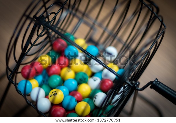 Multi-colored\
bingo balls in cage sitting on a\
desk.