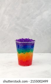 Multicolored Boba Drink Or Rainbow Bubble Tea In Disposable Plastic Cup. Refreshing Summer Cocktail On Grey Textured Background. Selective Focus, Copy Space.