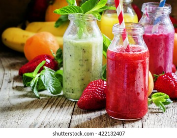 Multi-colored bottles with fresh fruit smoothies with striped straws, berries, fruit and mint leaves, vintage wooden background, selective focus - Powered by Shutterstock