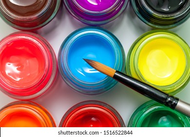 Multicolored bottles poster color and paintbrush on a white background Isolated Paints in containers Top view Copy space