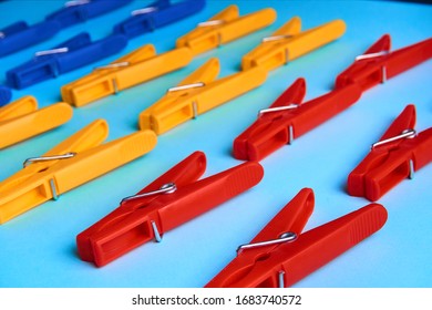 Multi-colored clothespins on a blue background lie in 3 rows.Bright objects.Perfectionism.Household.Close up