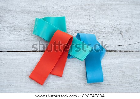 Multi-colored elastic rubber bands for fitness on a white wooden background. A set of rubber bands of different colors - red, blue and turquoise. Ideal for training at home.