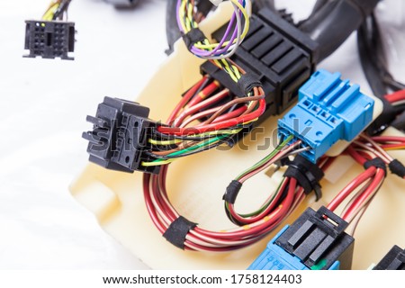 Multi-colored electrical wires with car connectors on a white isolated background during network repair by an engineer or mechanic in a service or workshop.