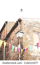 Multicolored festive bunting on narrow old street of a typical european town. Italy - Shutterstock ID 1136115377