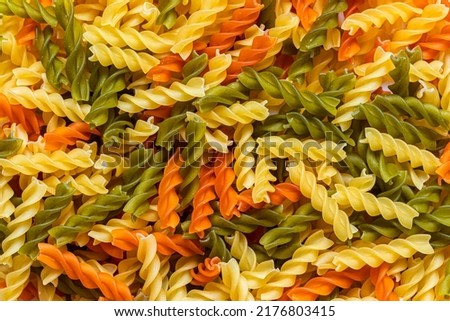 Multi-colored fusilli paste, with a spiral shape. Background image with an even layer of Italian spiral paste scattered