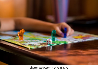 Multi-colored game chips with dice on the playing board. Board game.children sit in kindergarten at the table engaged, learn in the nursery,Playing table game.