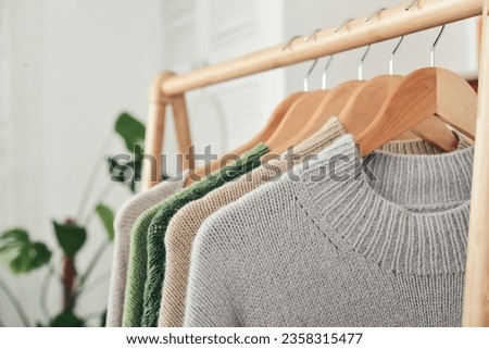 Multicolored handknitted sweaters on hangers closeup. Fashion concept.