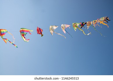 Multicolored Kites (Chinese) At The Sea Tied To A Thread. Kites Are Core To The Celebrations In China. Beyond Decorative And Festive Looks When They Fly Across The Sky, Kites Represent Traditional