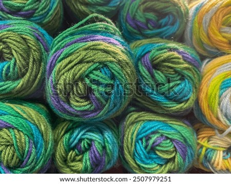multicolored knitting wool yarn thread balls in green, blue, purple, head on, fullframe
