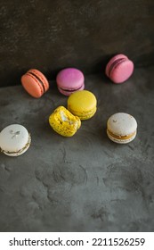 Multicolored macarons on the dark background. French almond dessert in different flavors on a table.