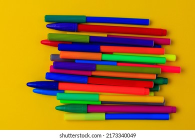 Multi-colored markers with mixed caps. Creative concept. Yellow background with selective focus and copy space for text