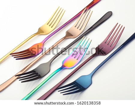 multi-colored metal forks on a white background, cutlery