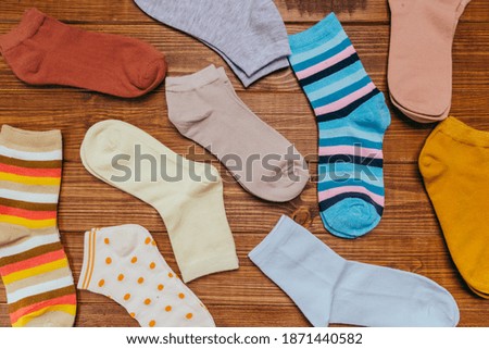 multicolored new socks in different sizes stacked on a wooden background. clothes for women. top view. place for text.