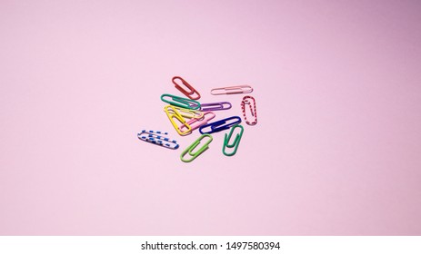Multi-colored paper clips on a pink background. - Shutterstock ID 1497580394