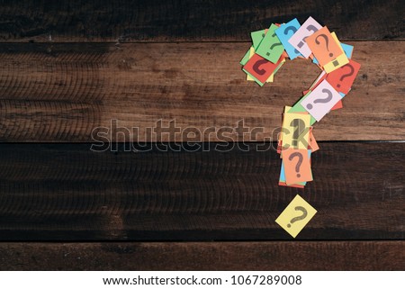multicolored paper with QUESTION MARK on a wooden table background. questions,mystery and diversity concept. FAQ and Q&A background concept
