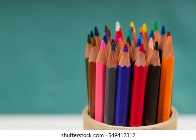 Multicolored pensils in the box on a blue background. Back to school. Copy space. Top view.