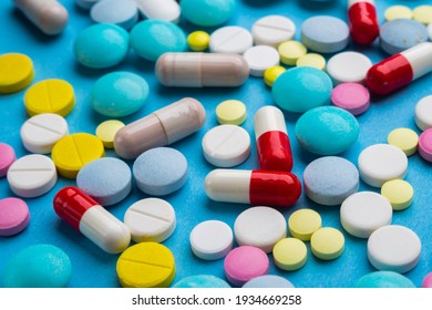 A lot of multicolored pills and capsules on a blue background as a concept of addiction from medicine. Vitamins to keep immunity on a high level.