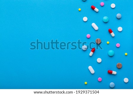 A lot of multi-colored pills on blue background with free space for text, as a concept of medical treatment with a prescription. Painkillers and antibiotics variation, allergy on medicine.