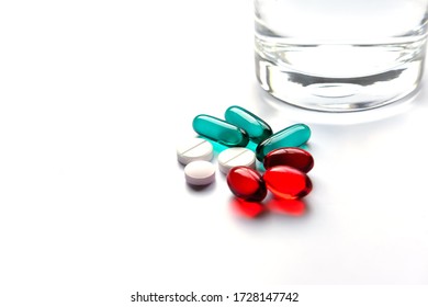 Multi-colored pills on white background with a glass of water. Healthcare concept. - Powered by Shutterstock