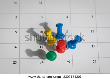 Multicolored pins on one date on a calendar. Busy and fully booked schedule concept.