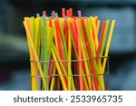 Multi-colored, plastic, disposable drinking straws with bellows standing upright in a wire container. 