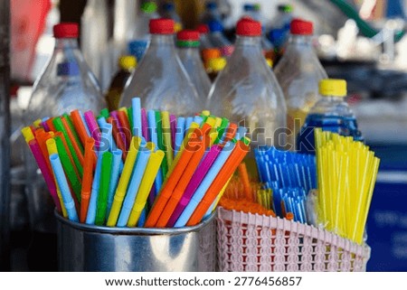 Multi-colored, plastic, disposable drinking straws with bellows standing upright in a shiny, silver metal container. 