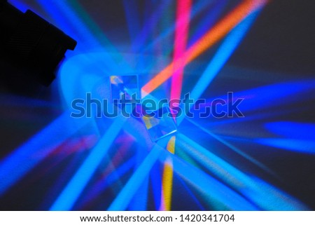 multicolored rays of light are refracted and divided into a spectrum in a glass prism on a dark background