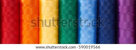 Multicolored sewing threads arrange like rainbow, background